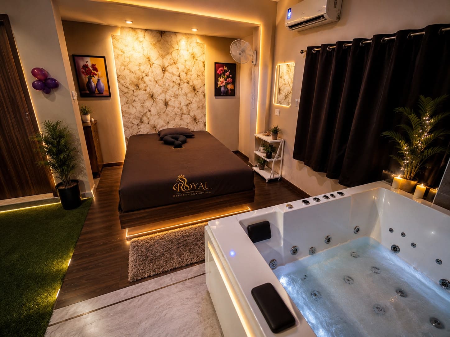 Jacuzzi room with a white jetted tub lit in soft blue, a bed with Royal Refresh linens and candles by the window